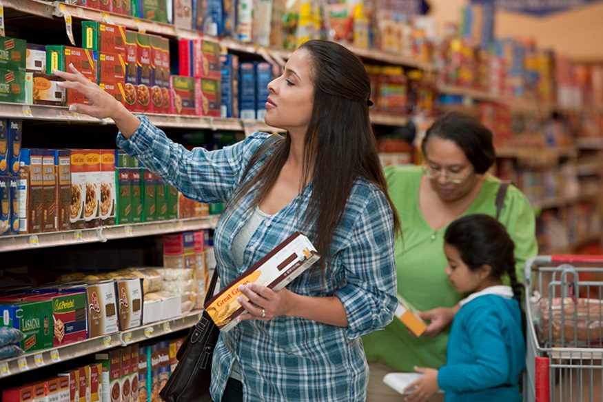 Woman in the grocery store looking at a box of pasta